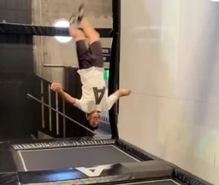 Enfant faisant un saut acrobatique tête en bas sur un trampoline dans le parc Airloop à Genève