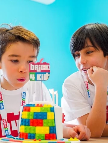 Deux garçons concentrés construisant une tour en briques LEGO colorées lors d'un anniversaire Bricks 4 Kidz