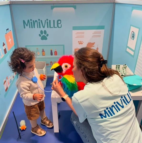 Petite fille jouant à la vétérinaire avec une animatrice Miniville et une peluche perroquet coloré