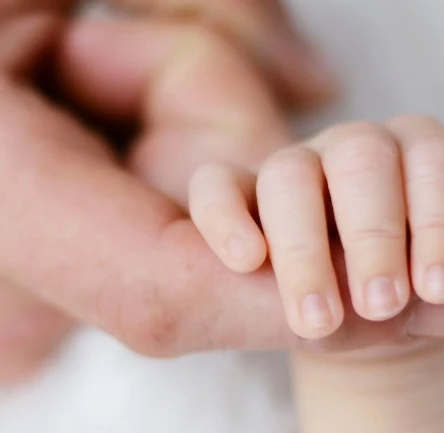 Main d'un bébé agrippant doucement le doigt d'un parent – lien parent-enfant