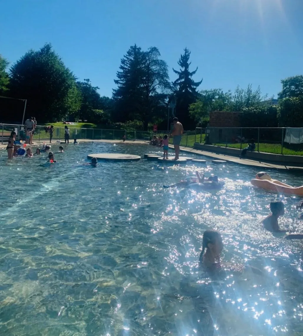 Enfants et parents barbotant dans la pataugeoire de La Caroline à Petit-Lancy par beau temps