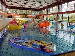 Bassin intérieur de la piscine de Thônex avec enfants et bouées colorées