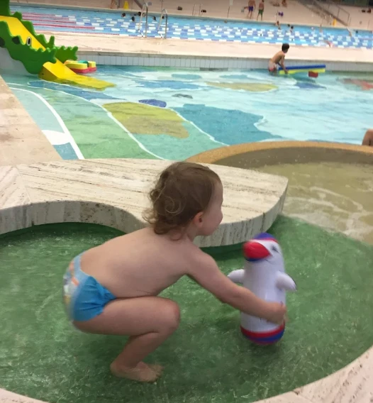 Petit enfant jouant avec un jouet gonflable dans la pataugeoire intérieure de la piscine des Vernets, Genève.