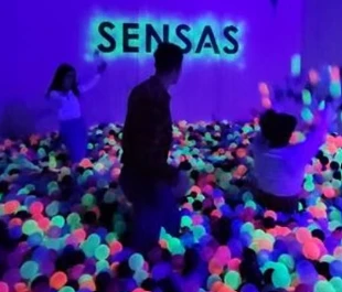 Enfants et adultes jouant dans une piscine de balles lumineuses dans la salle Sensas à Genève