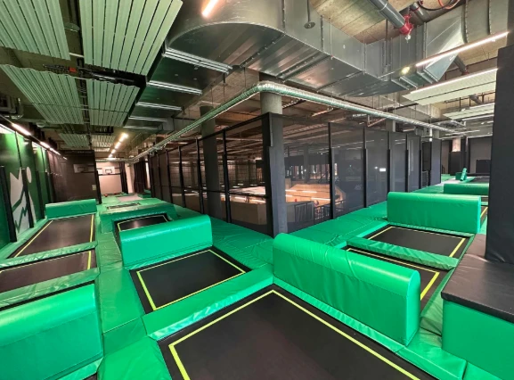 Vaste salle de trampoline indoor avec trampolines verts alignés, TOTEM Vernier