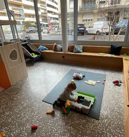 Enfant jouant sur un tapis dans l'espace de jeu lumineux du Café Lumen, Genève