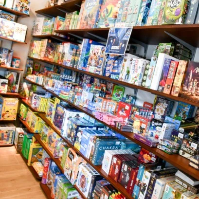 Rayonnages colorés du magasin L'Astuce Jeux à Carouge, remplis de jeux de société pour tous les âges.