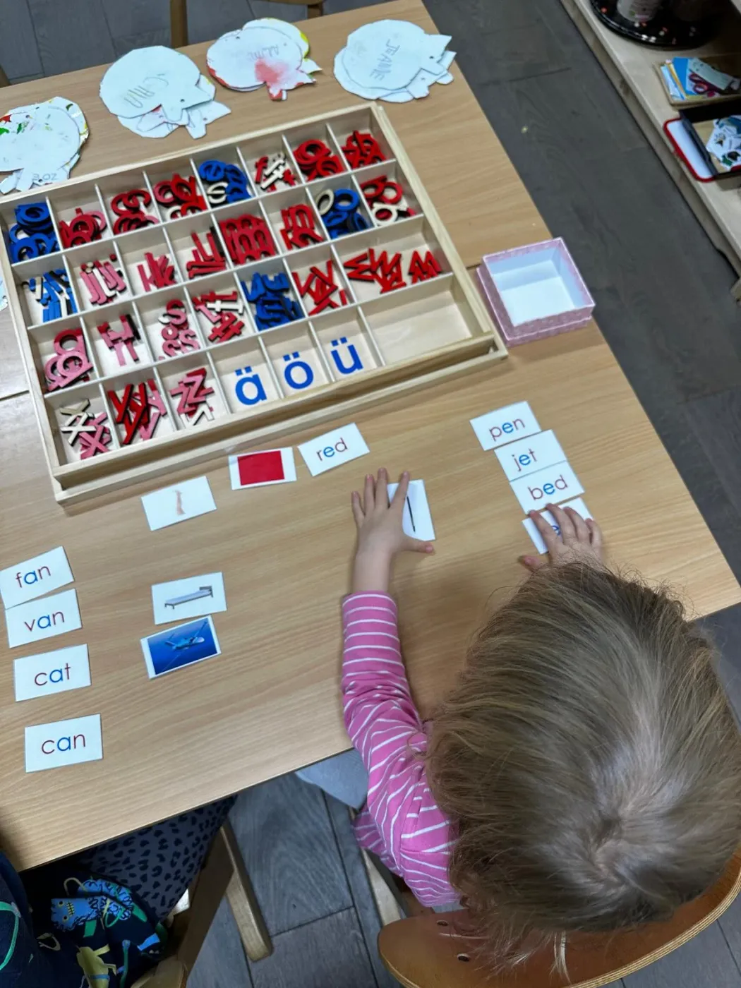 Enfant manipulant des lettres Montessori et des cartes de mots en anglais sur une table en bois