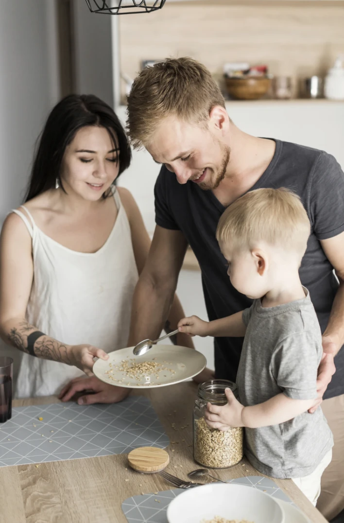 Famille avec un jeune enfant préparant un repas sain ensemble dans leur cuisine