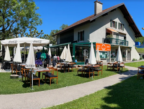 Terrasse ensoleillée du restaurant Drizia Miremont avec tables, parasols et jardin, route de Vessy, Genève