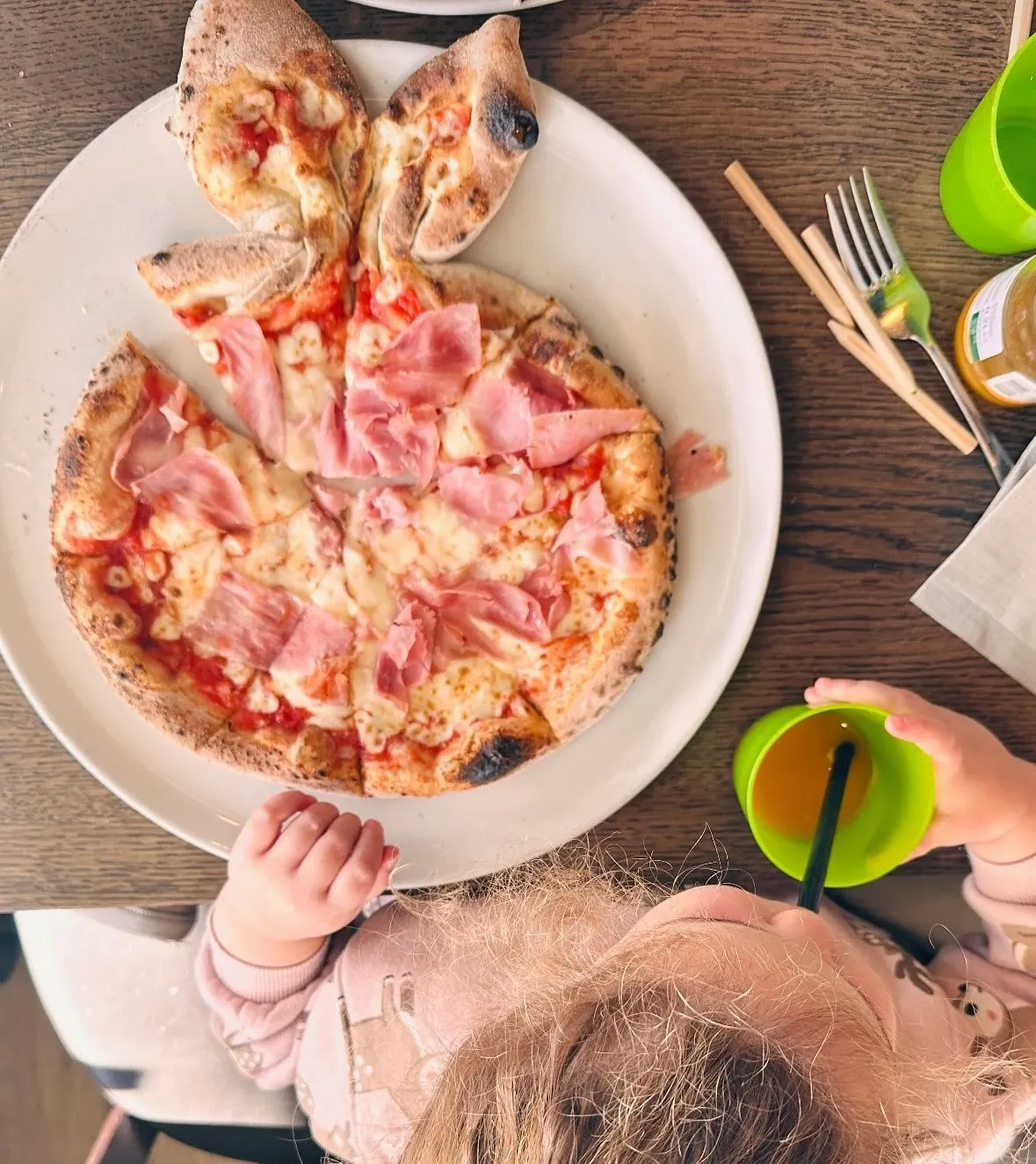 Pizza au jambon cuite au feu de bois aux Tilleuls, avec un jeune enfant attablé à côté, à Genève