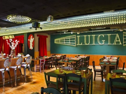 Salle du restaurant Luigia avec tables dressées et enseigne lumineuse, ambiance italienne chaleureuse