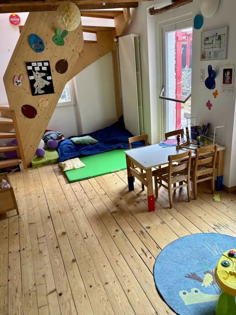 Salle de jeux pour enfants du restaurant Un R de Famille à Genève, avec tapis, table et mur d'escalade en bois