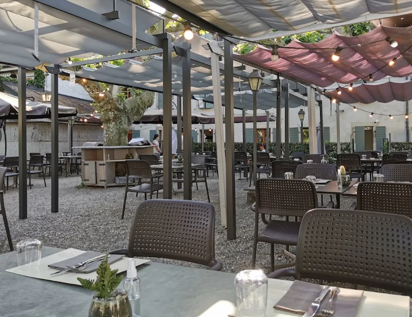 Grande terrasse ombragée du Vicolo39 à Carouge, tables dressées sous pergola et guirlandes lumineuses