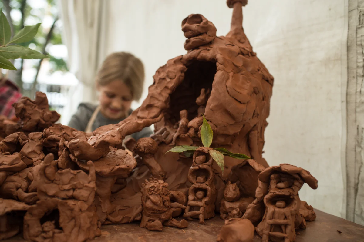 Enfant modelant des figurines en terre lors d'un atelier céramique parents-enfants