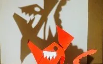 Sculpture en papier orange en forme de renard avec son ombre projetée sur un mur