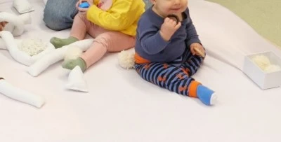 Deux bébés assis sur un tapis blanc jouant avec des jouets