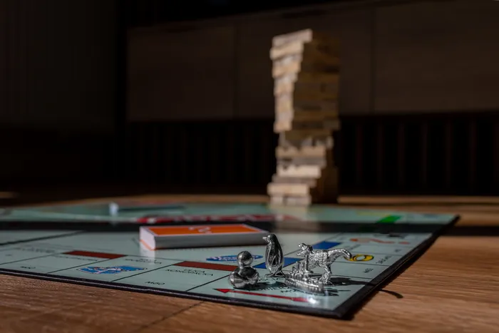 Plateau de Monopoly avec pions en métal et tour de Jenga en bois en arrière-plan